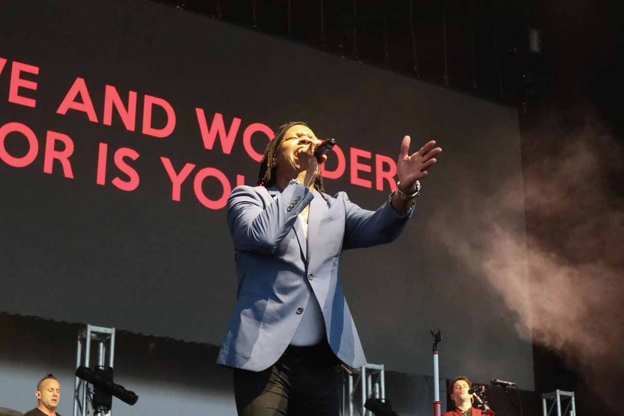 Michael Tait sings with one arm extended under concert lighting.