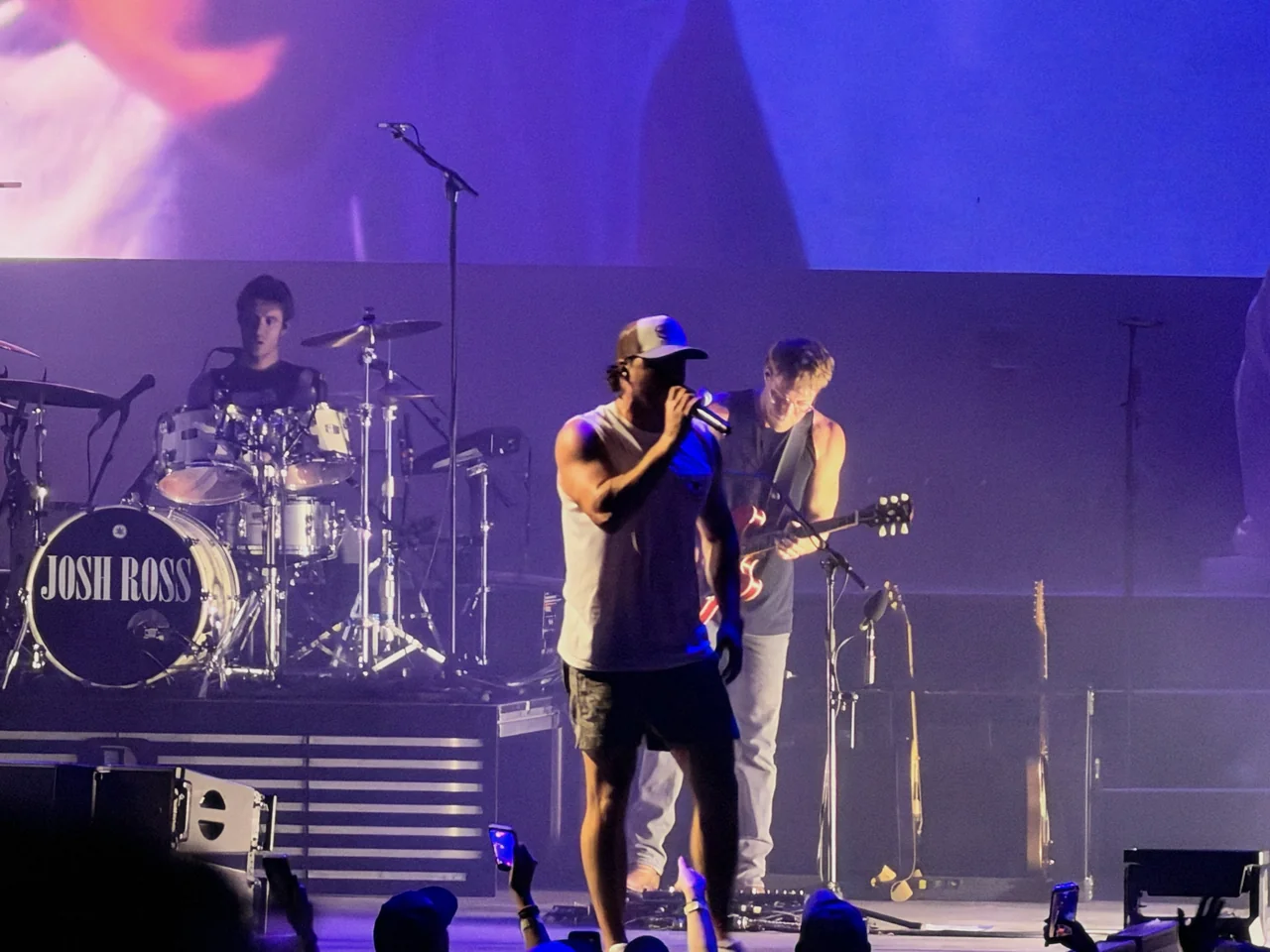 Josh Ross singing beside his guitarist, with his name on the bass drum.