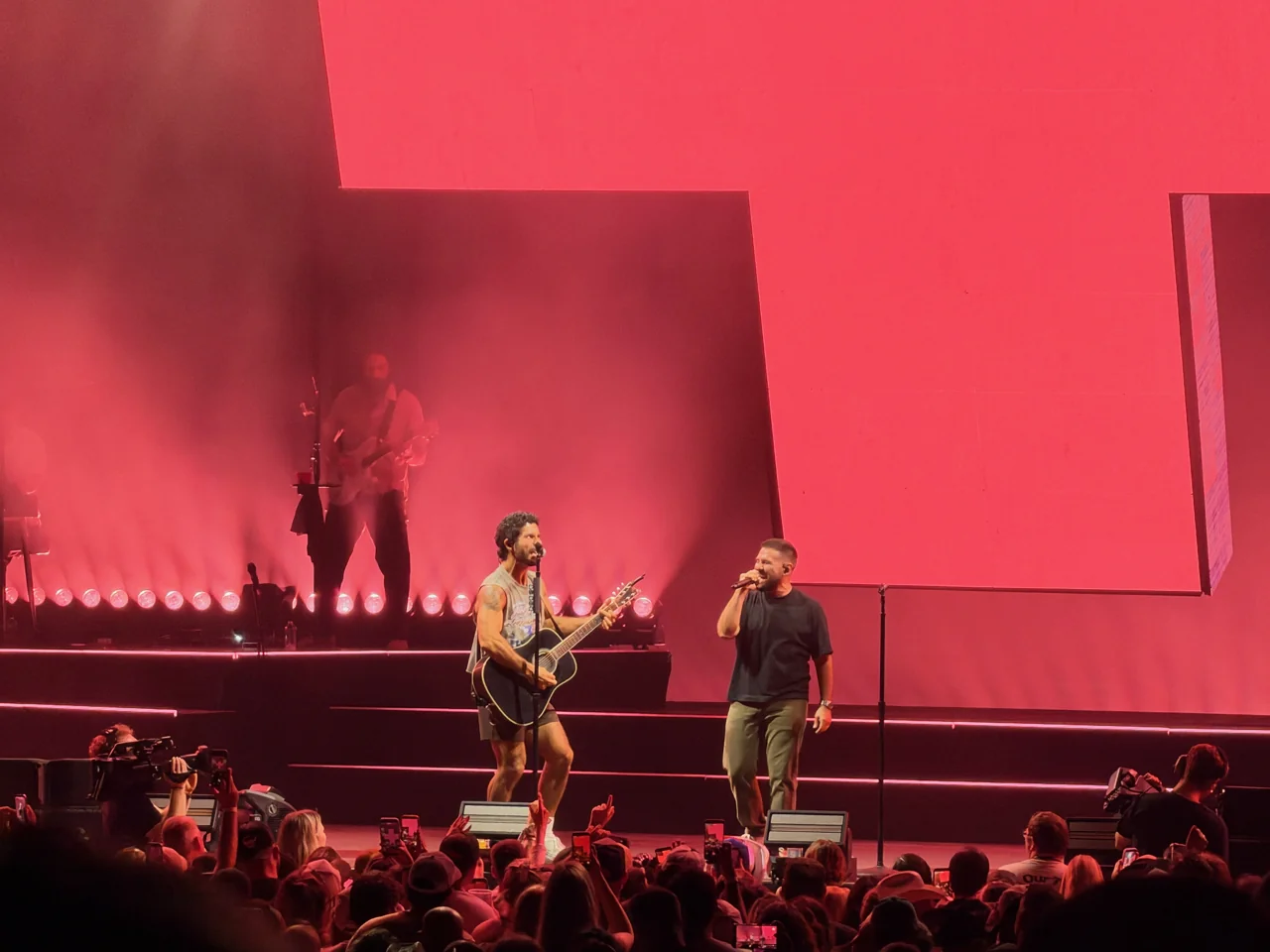 Dan + Shay performing against a red stage backdrop.