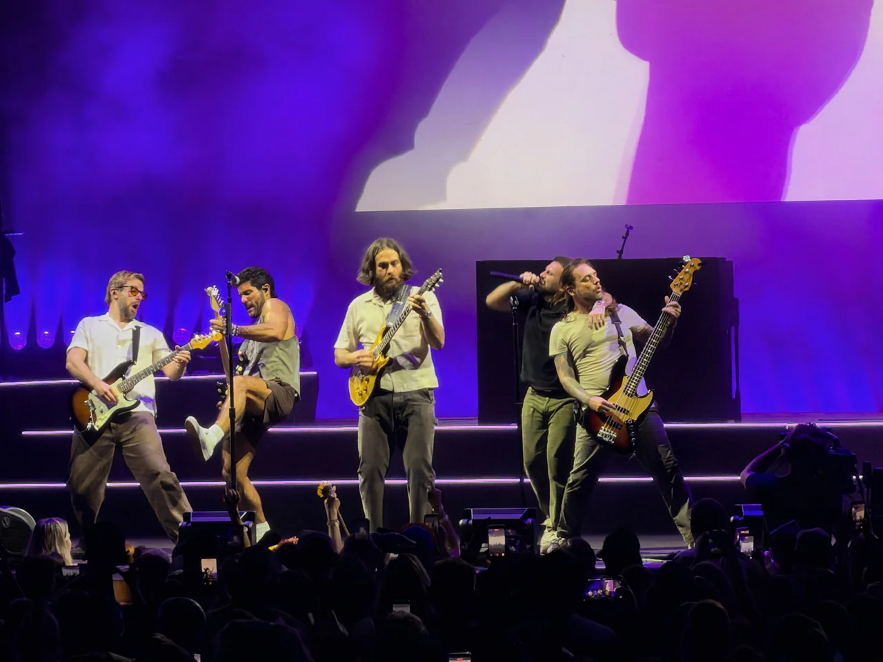 Dan + Shay and band together under purple stage lighting.