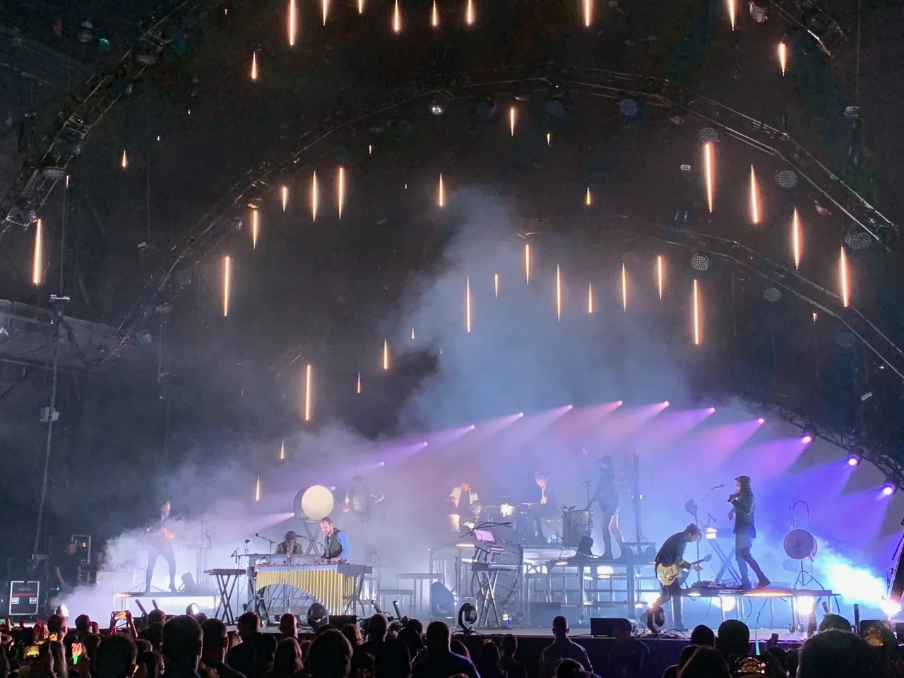 for KING & COUNTRY performing across several platforms beneath hanging amber lights and purple beams.