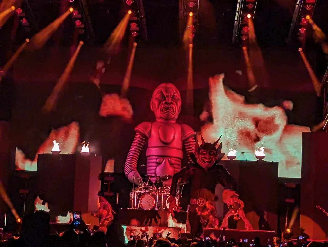 Rob Zombie performing on a stage with a giant monster prop and flame effects.