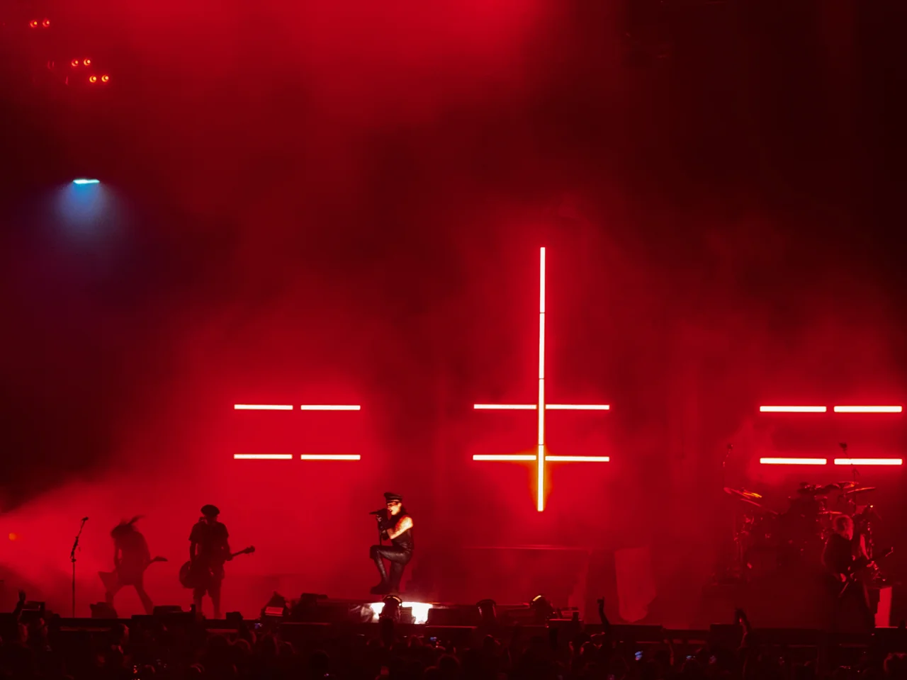 Marilyn Manson silhouetted beneath red illuminated crosses.
