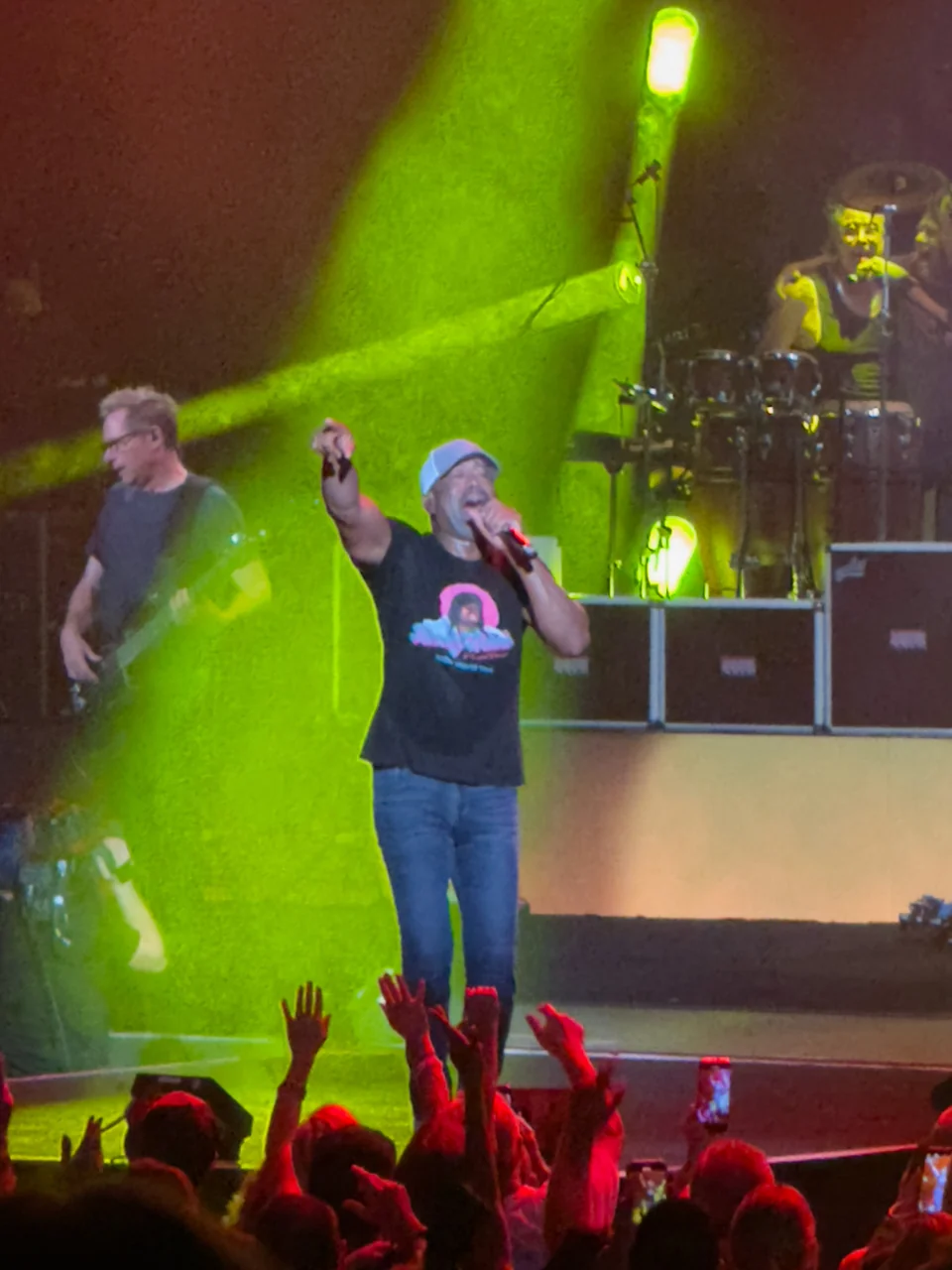 Darius Rucker singing and pointing toward the audience under green stage light.