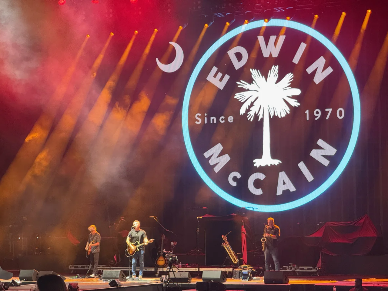 Edwin McCain and his band performing beneath a circular backdrop bearing his name.