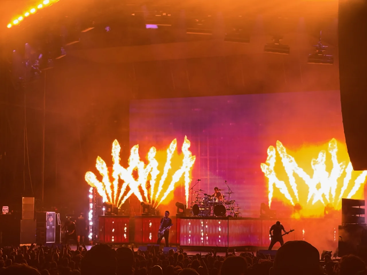 Gojira performing in silhouette below two fans of flame jets.