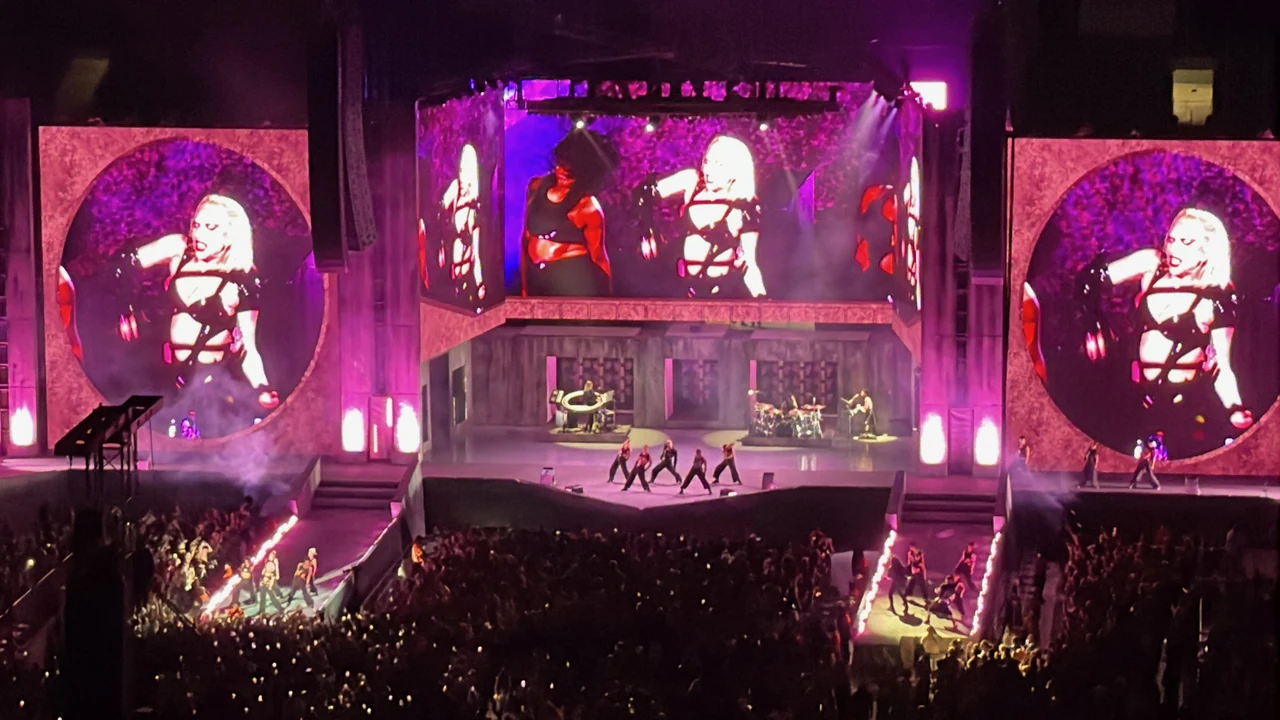 Lady Gaga and dancers on the Chromatica Ball stage, with her image on large video screens, purple lighting, and flames lining the audience runways.